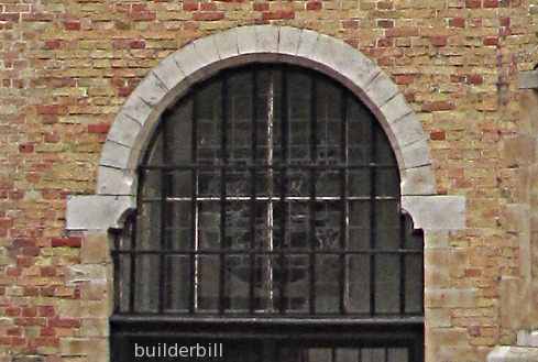 a stonework bell arch in a brick wall