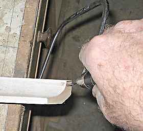 Using a coping saw to cut a scribe to a cornice