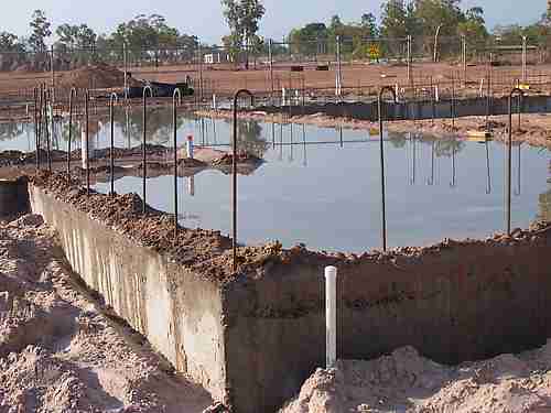 Curing a concrete house slab by flooding